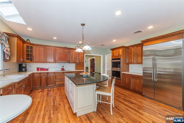 kitchen with a breakfast bar, sink, dark stone counters, a kitchen island, and stainless steel appliances