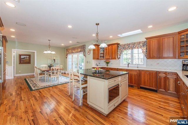 kitchen featuring a kitchen bar, light hardwood / wood-style flooring, a kitchen island, pendant lighting, and dark stone counters