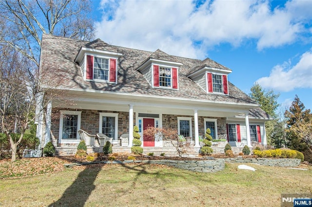 new england style home featuring a front yard and covered porch