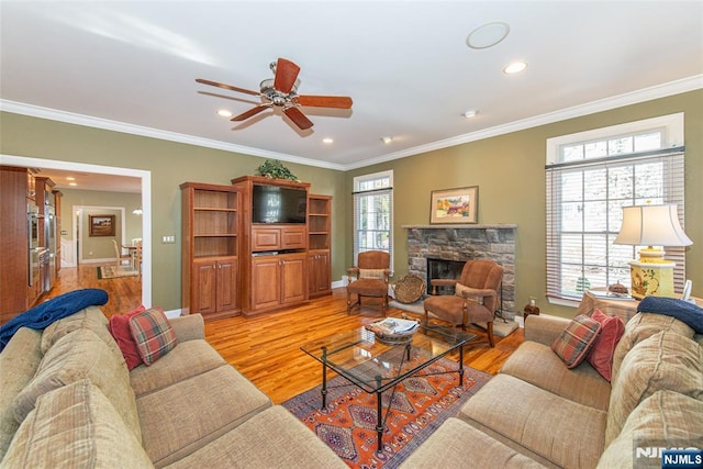 living room with crown molding, plenty of natural light, a fireplace, and light hardwood / wood-style floors