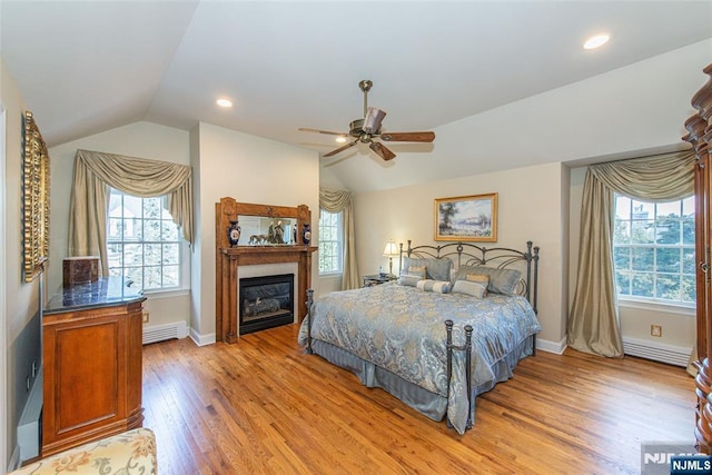 bedroom with ceiling fan, lofted ceiling, a baseboard heating unit, and light wood-type flooring