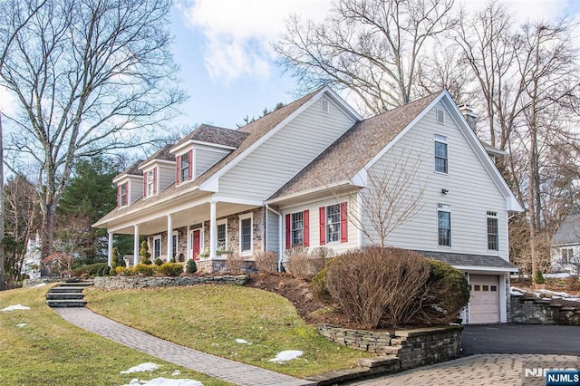 cape cod house with a garage, covered porch, and a front lawn