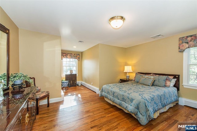 bedroom featuring hardwood / wood-style flooring and a baseboard heating unit