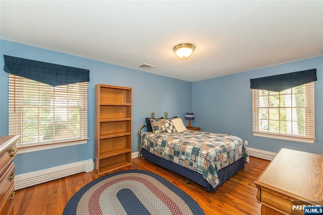 bedroom with a baseboard heating unit and dark wood-type flooring