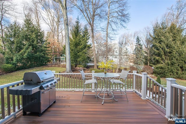 wooden deck featuring a playground and area for grilling