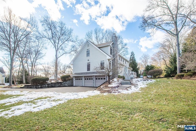 view of snowy exterior with a garage and a lawn