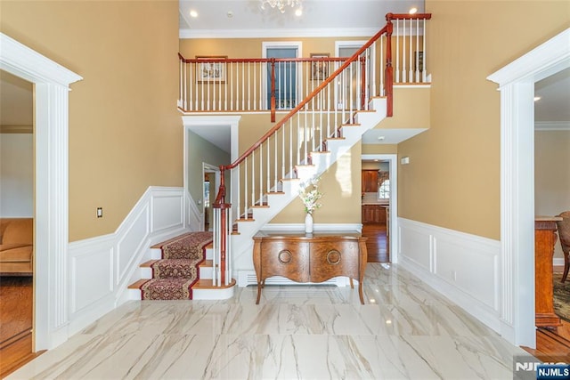 stairway with crown molding and a high ceiling