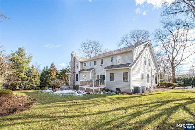 rear view of property with cooling unit, a wooden deck, and a yard