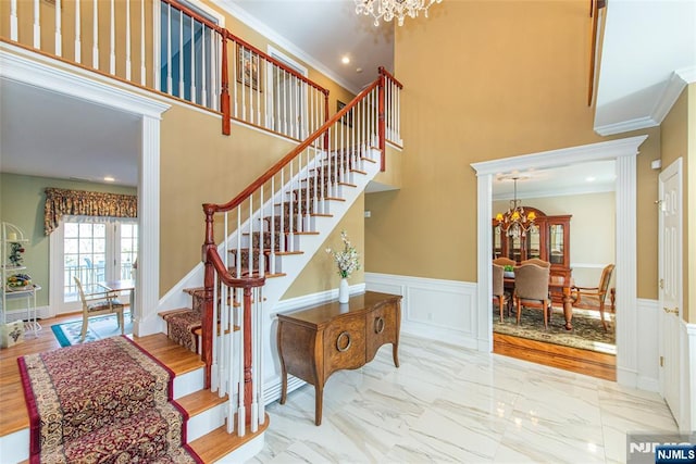 staircase with ornamental molding, a chandelier, and a high ceiling