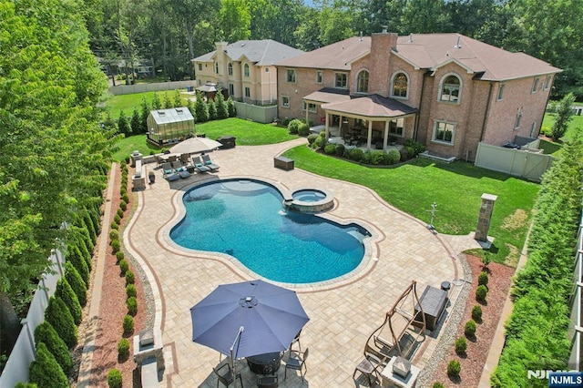 view of swimming pool featuring a yard, an outbuilding, a patio area, and an in ground hot tub