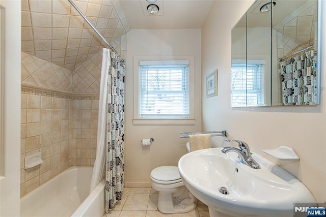 full bathroom with a healthy amount of sunlight, tile patterned floors, toilet, and shower / bath combo