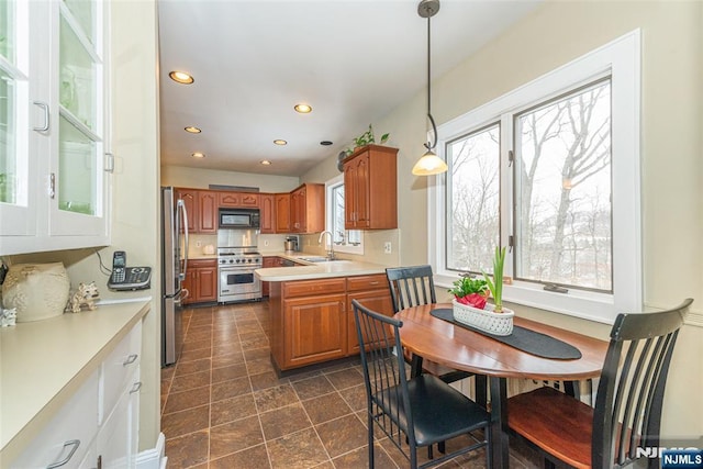 kitchen with pendant lighting, sink, stainless steel appliances, and kitchen peninsula