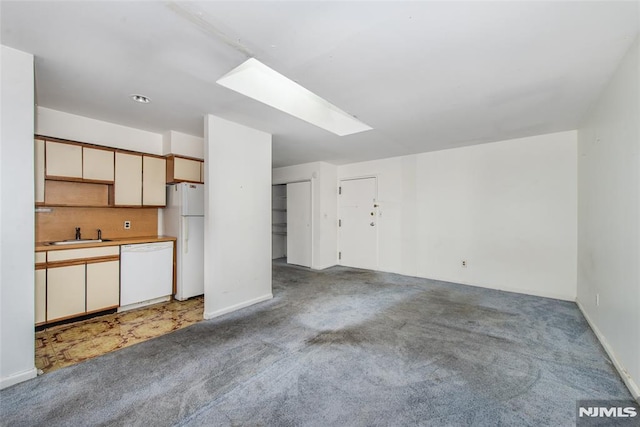 kitchen with sink, a skylight, white appliances, carpet, and backsplash