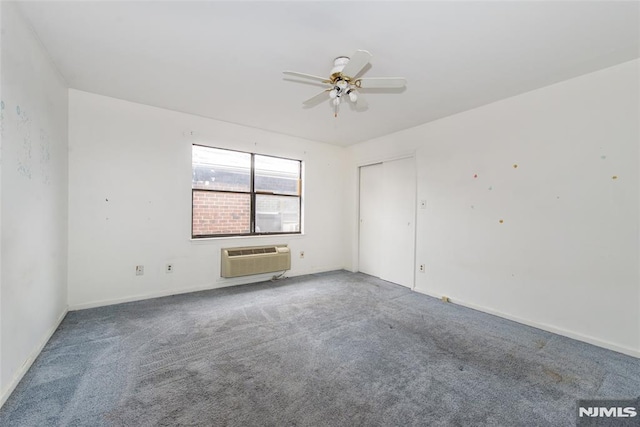 carpeted spare room featuring a wall mounted air conditioner and ceiling fan