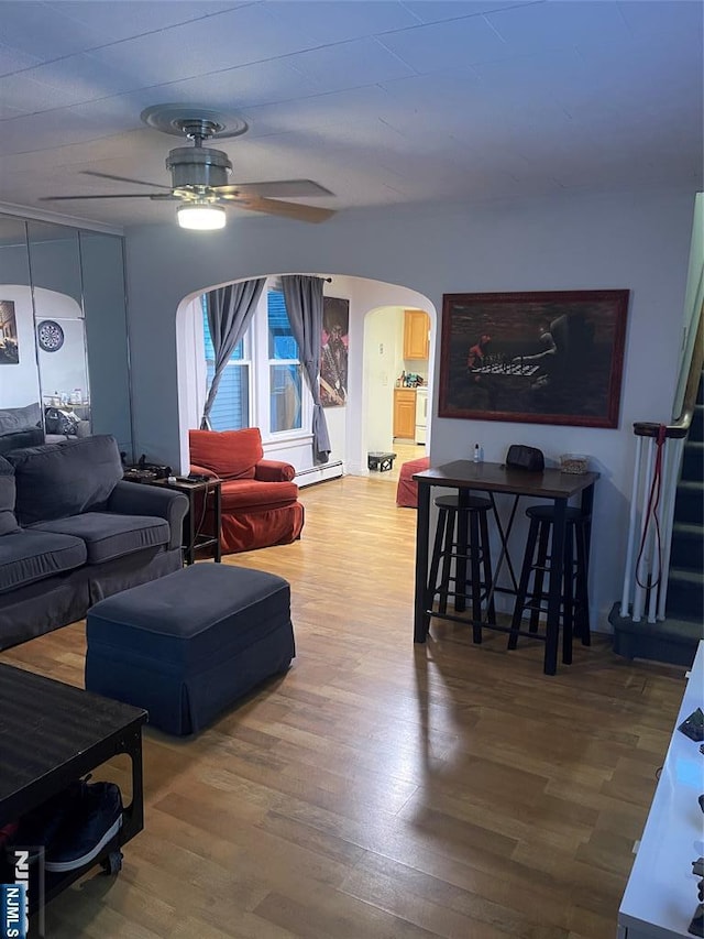 living room with a baseboard heating unit, hardwood / wood-style floors, and ceiling fan