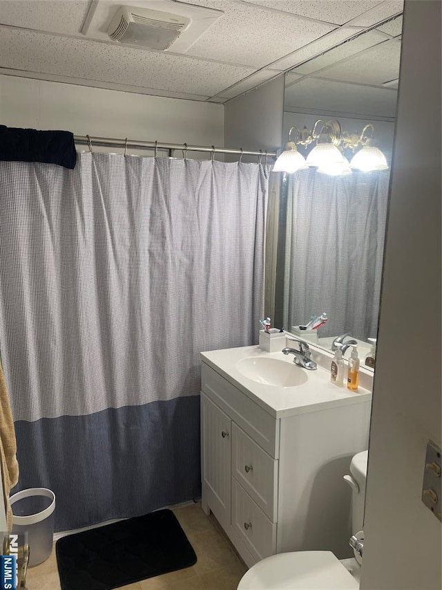 bathroom with a drop ceiling, vanity, and toilet