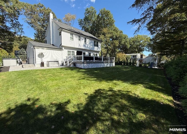 back of house featuring a lawn and a deck