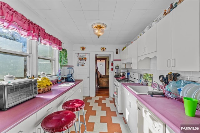 kitchen featuring tasteful backsplash, white cabinetry, sink, and white appliances