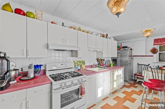 kitchen with tasteful backsplash, sink, white cabinets, and white appliances