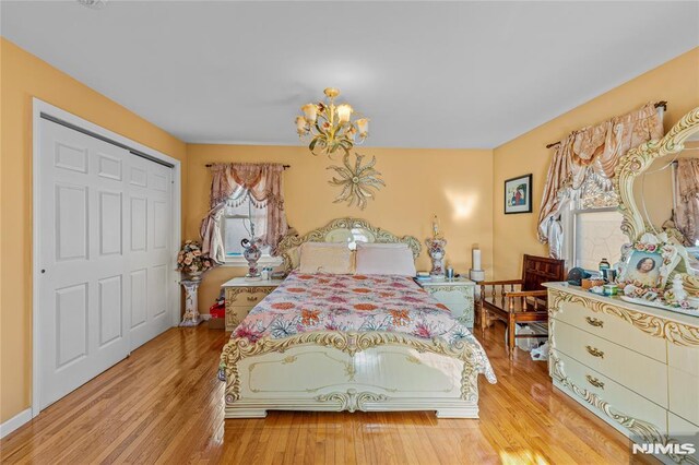 bedroom with a notable chandelier, light hardwood / wood-style flooring, and a closet