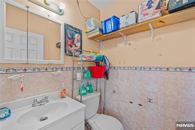 bathroom with vanity, tile walls, and toilet