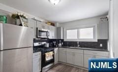 kitchen with refrigerator, sink, dark hardwood / wood-style flooring, decorative backsplash, and stove