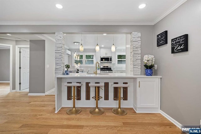 bar with pendant lighting, sink, light hardwood / wood-style flooring, stainless steel appliances, and white cabinets