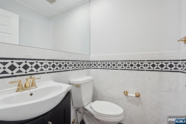 bathroom featuring vanity, tile walls, and toilet