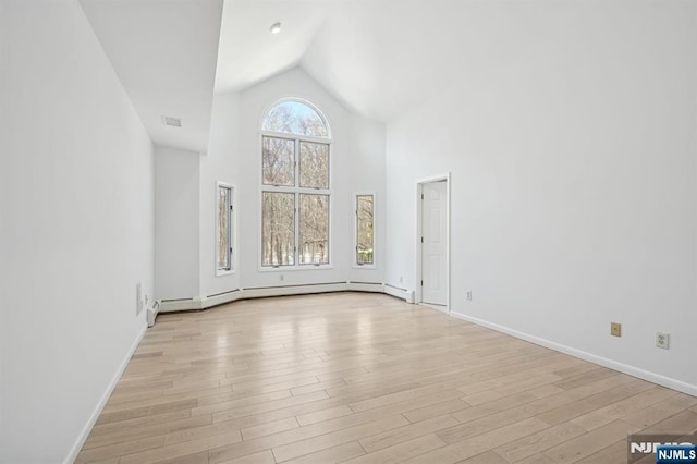 interior space with a baseboard heating unit, high vaulted ceiling, and light hardwood / wood-style flooring