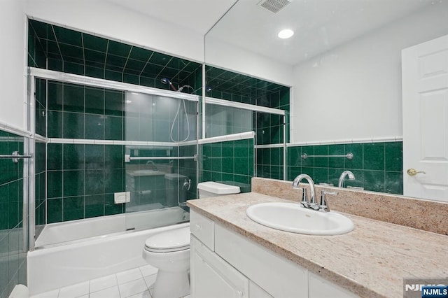 full bathroom featuring bath / shower combo with glass door, vanity, tile patterned floors, and toilet