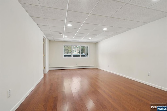 spare room featuring hardwood / wood-style floors, a baseboard radiator, and a paneled ceiling