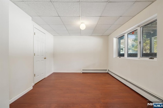 spare room featuring a drop ceiling, a baseboard radiator, and wood-type flooring