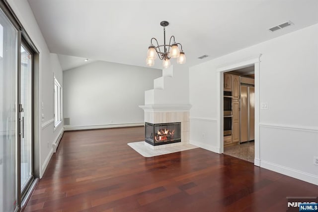 unfurnished living room featuring a tile fireplace, vaulted ceiling, a baseboard heating unit, and dark hardwood / wood-style floors