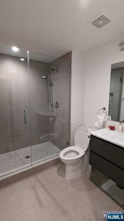 bathroom with tile patterned flooring, vanity, a shower with shower door, and toilet