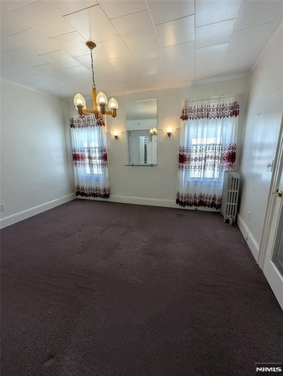 carpeted empty room with ornamental molding, plenty of natural light, radiator, and an inviting chandelier