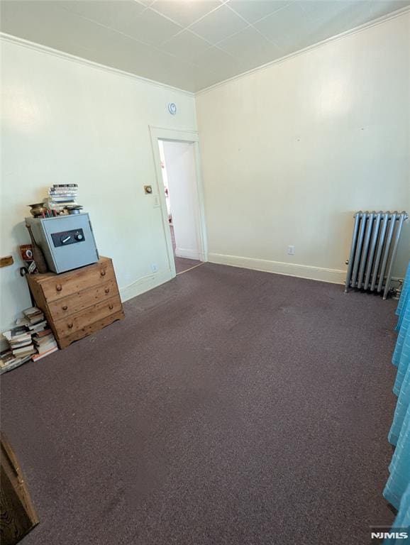 unfurnished room featuring ornamental molding, radiator heating unit, and dark colored carpet