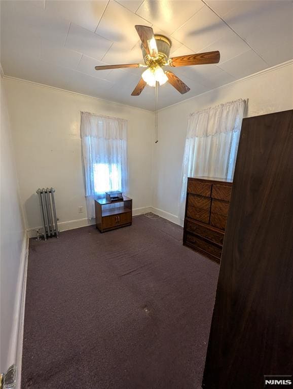 unfurnished bedroom with ceiling fan, ornamental molding, radiator, and dark colored carpet