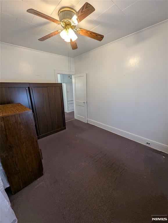 unfurnished bedroom with crown molding, ceiling fan, and dark carpet