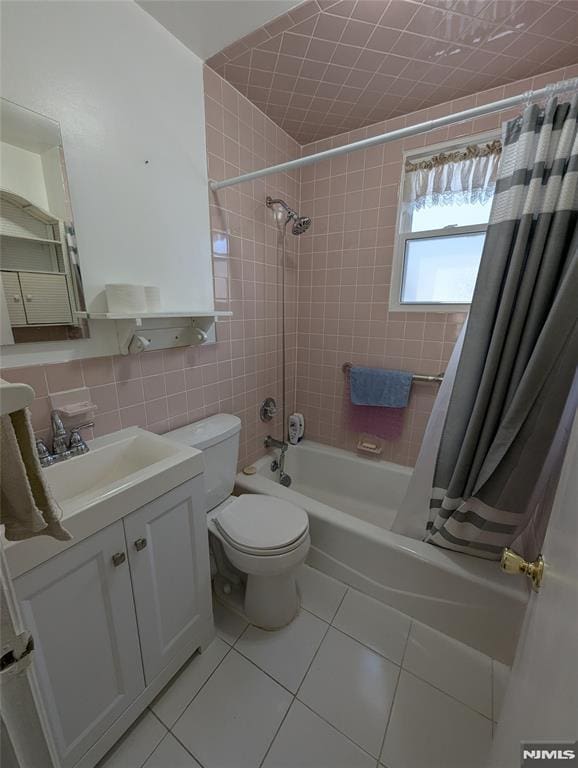 full bathroom with tile patterned floors, toilet, tile walls, vanity, and shower / bath combination with curtain