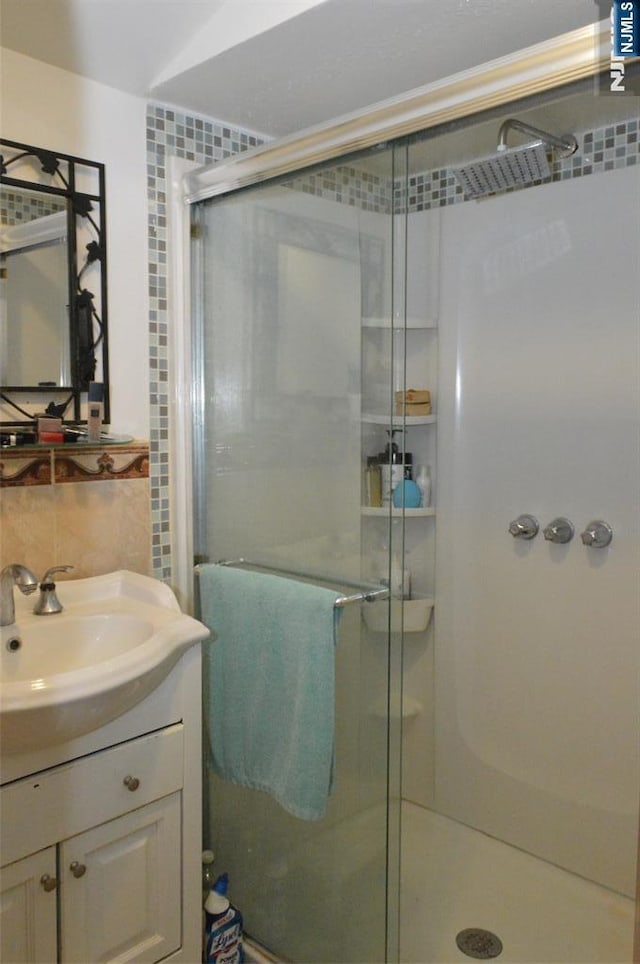 bathroom featuring vanity, backsplash, and walk in shower