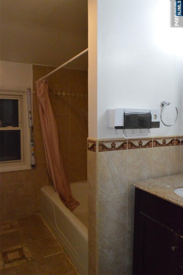 bathroom with shower / bath combination with curtain, vanity, tile patterned flooring, and tile walls