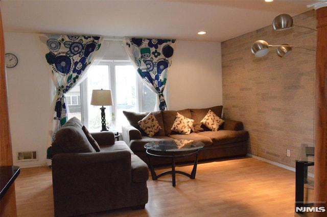 living room featuring wood-type flooring and brick wall