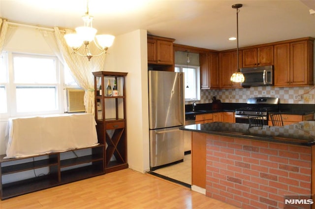 kitchen featuring appliances with stainless steel finishes, pendant lighting, sink, light hardwood / wood-style floors, and plenty of natural light