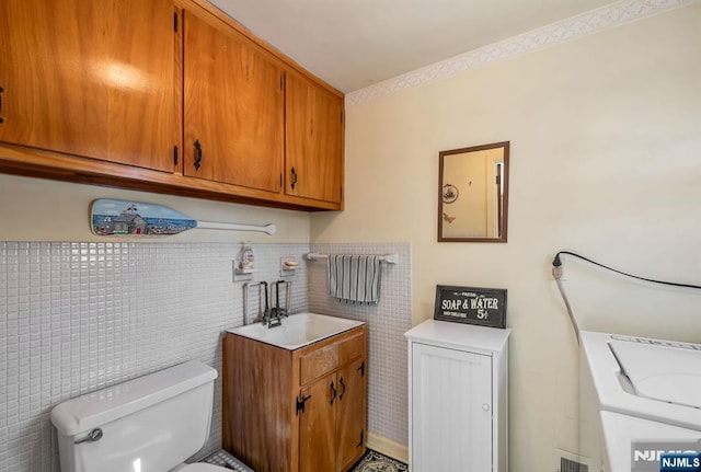 laundry area featuring sink and tile walls