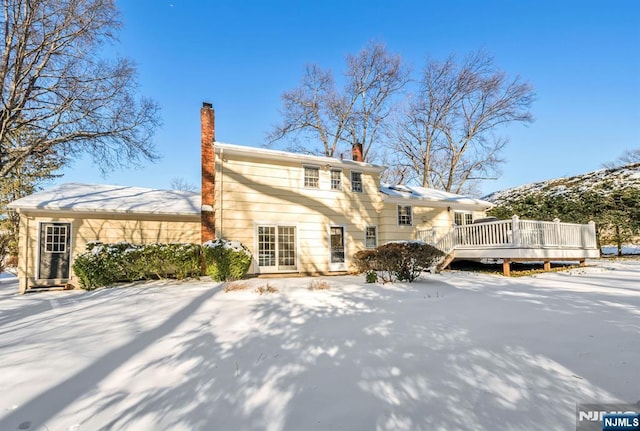 snow covered house featuring a wooden deck