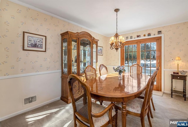 dining area featuring crown molding, light colored carpet, and a notable chandelier