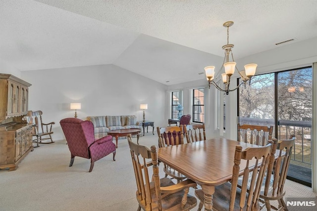 dining room with an inviting chandelier, vaulted ceiling, light carpet, and a textured ceiling