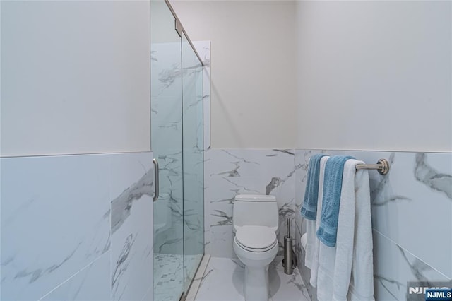 bathroom featuring toilet, a shower with door, and tile walls