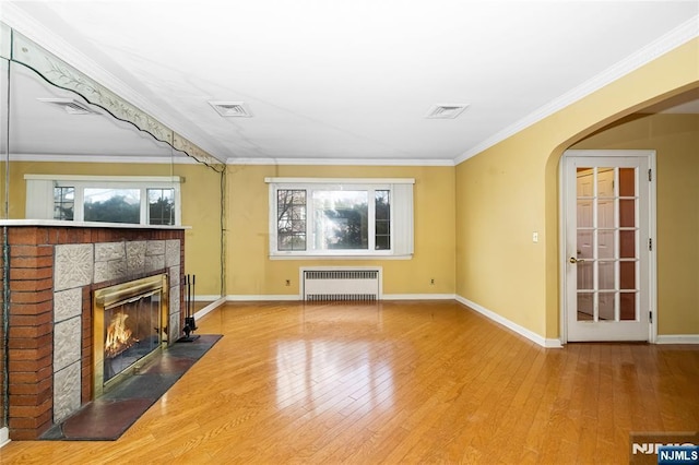 unfurnished living room with hardwood / wood-style floors, radiator heating unit, and ornamental molding