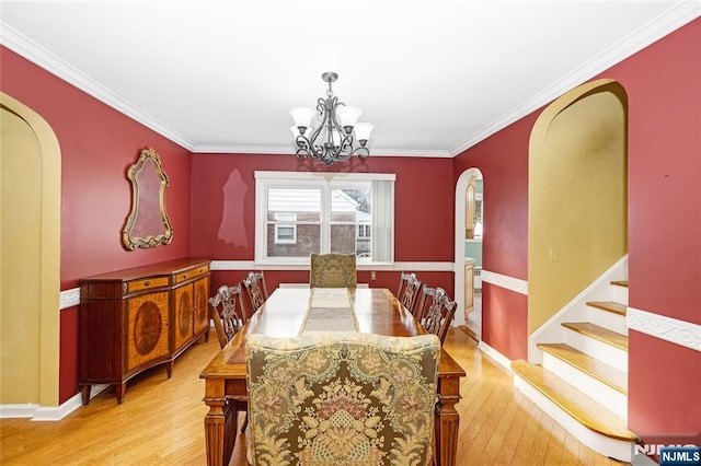 dining space with an inviting chandelier, ornamental molding, and light wood-type flooring